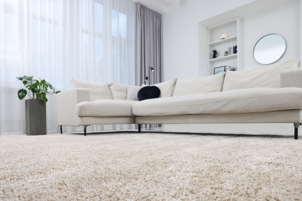 Low angle picture of beige carpet and beige coloured L shape sofa