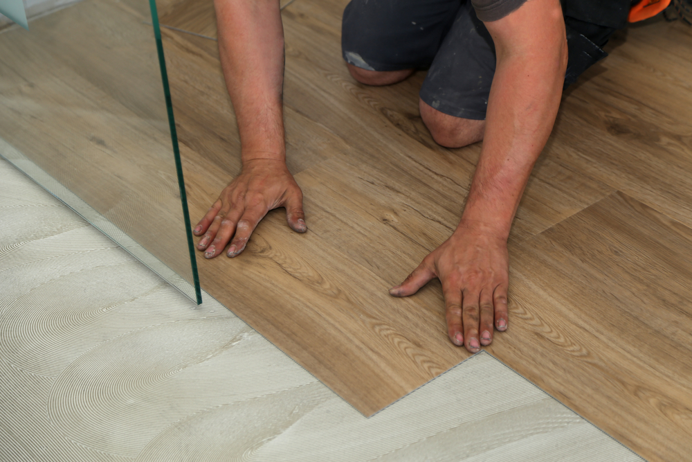 man installing lvt flooring in bathroom